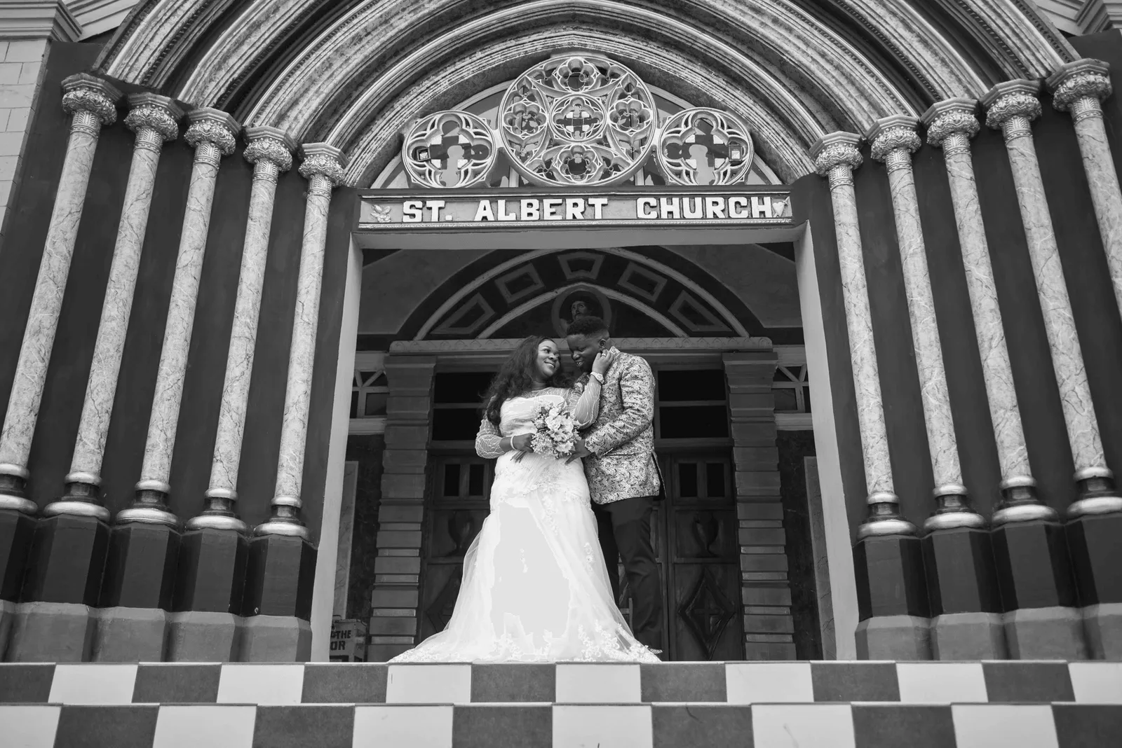 Black and white photograph of a bride and groom under the columns of St. Albert Church