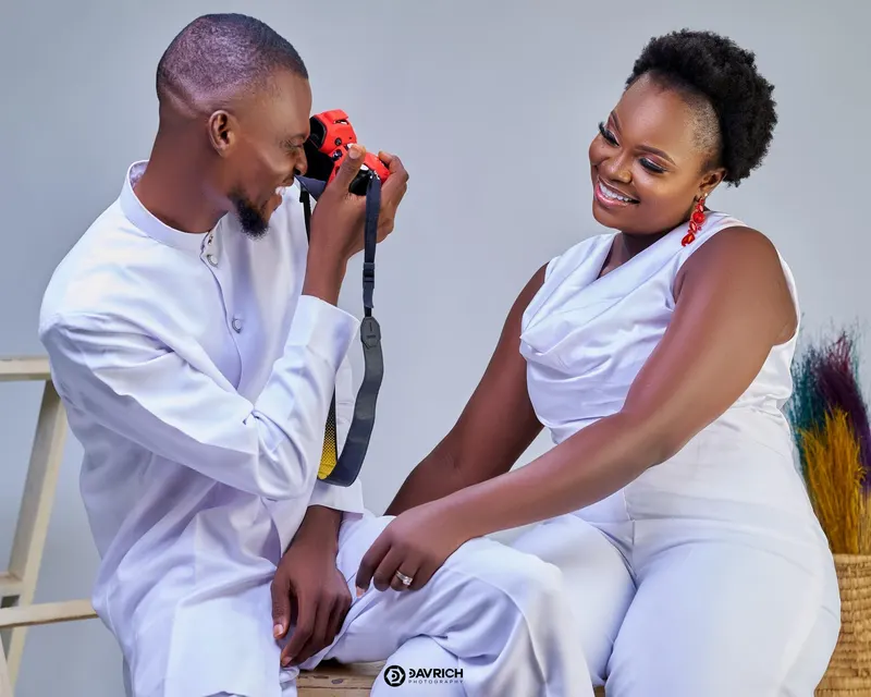 Man in a white kaftan photographing his laughing partner with a red camera